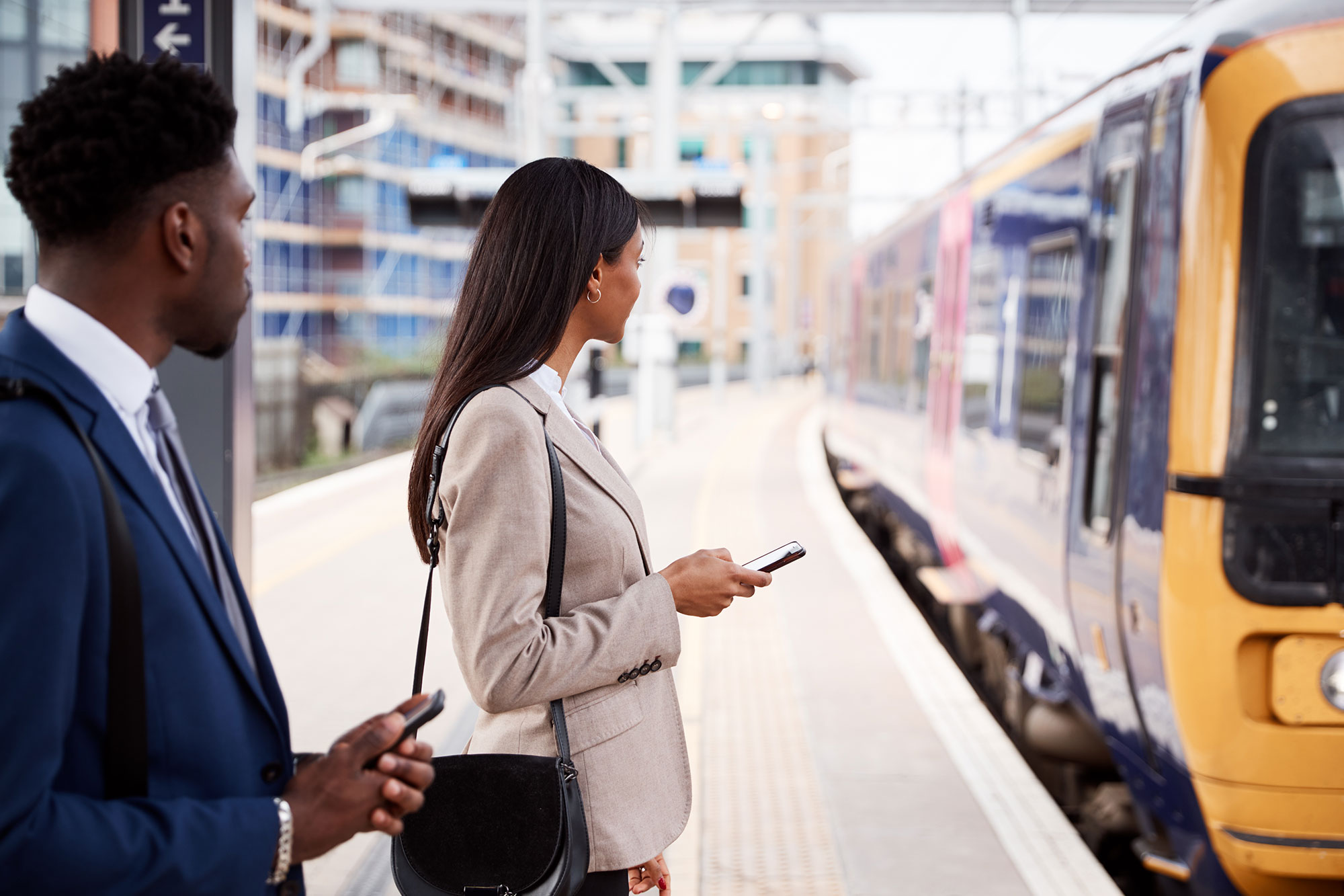 A man and woman in business attire wait for the MBTA Commuter Rail